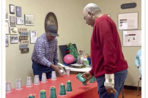 Terry French beats his Uncle Joel French at a game of flipping an object into the air and catching it into the cup.